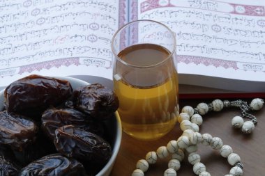 Arapça kutsal Kur 'an, tespih, bir bardak çay ve taze hurma. İslam sembolleri ve Ramazan Kareem kavramı. 