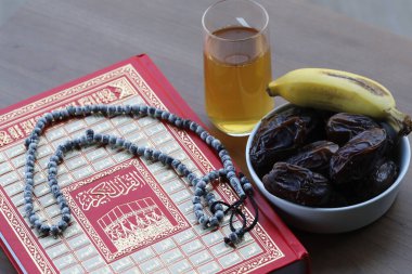 Arapça kutsal Kur 'an, tespih, bir bardak çay ve taze hurma. İslam sembolleri ve Ramazan Kareem kavramı. 