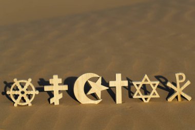 Günbatımında kumdaki dini semboller: Katolik, İslam, Yahudilik, Ortodoksluk, Protestan, Budizm ve Hinduizm. Dinlerarası, dinler arası ve ruhsallık kavramı.