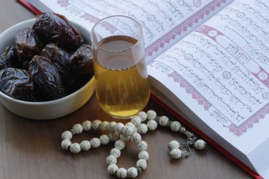 Arapça kutsal Kur 'an, tespih, bir bardak çay ve taze hurma. İslam sembolleri ve Ramazan Kareem kavramı. 