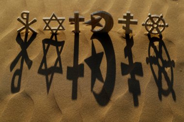 Günbatımında kumdaki dini semboller: Katolik, İslam, Yahudilik, Ortodoksluk, Protestan, Budizm ve Hinduizm. Dinlerarası, dinler arası ve ruhsallık kavramı.