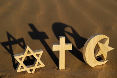 Gün batımında kumdaki dini semboller: Yahudi Davut Yıldızı, Müslüman Yıldızı ve Hilal ve Catholc Haçı. Dinlerarası, dinler arası ve ruhsallık kavramı