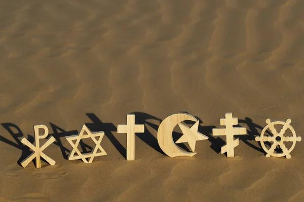 stock image Religious symbols on sand at sunset :  Catholic, Islam, Judaism, Orthodoxy, Protestant, Buddhism and Hinduism. Interreligious, interfaith and spirituality concept.