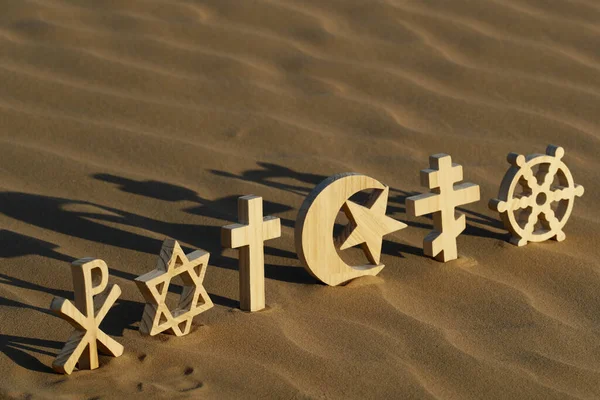 Günbatımında kumdaki dini semboller: Katolik, İslam, Yahudilik, Ortodoksluk, Protestan, Budizm ve Hinduizm. Dinlerarası, dinler arası ve ruhsallık kavramı.