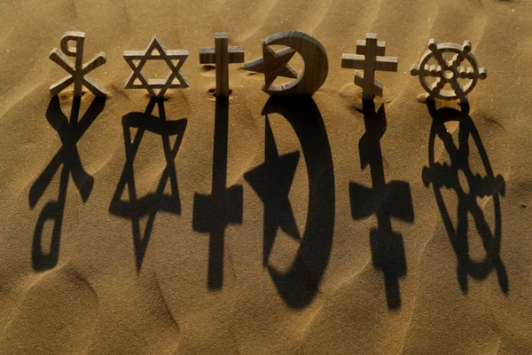 stock image Religious symbols on sand at sunset :  Catholic, Islam, Judaism, Orthodoxy, Protestant, Buddhism and Hinduism. Interreligious, interfaith and spirituality concept.