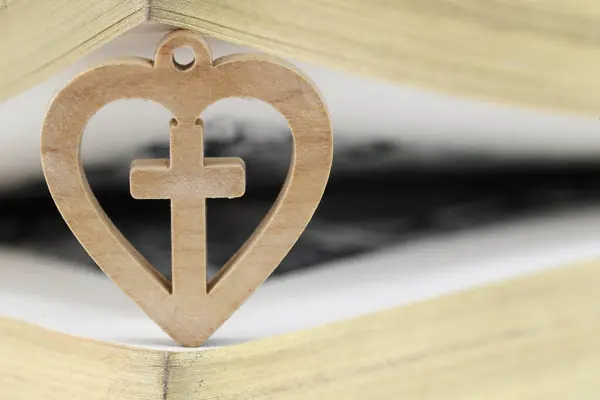 Bible with wooden heart with christian cross. Love and religion concept.