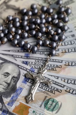 Para ve din. Amerikan dolarlarının banknotları ve tespihi. Katolik finans, ekonomi ve inanç kavramı. 