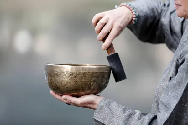 Tibetan bowl is used in sound therapy, meditation and yoga. Woman practicing a singing bowl for sound therapy in atmosphere for healing, meditation and relax.  France.