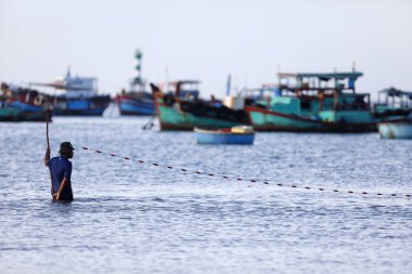 Balıkçı ağıyla balık tutmaya çalışıyor. Vung Tau. Vietnam.