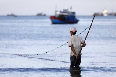 Balıkçı ağıyla balık tutmaya çalışıyor. Vung Tau. Vietnam.