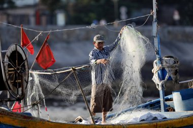 Balıkçı balık ağlarını tamir ediyor. Dua hangarını asın. Vung Tau. Vietnam.