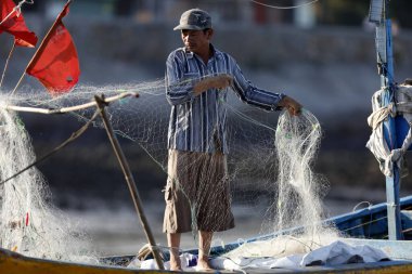 Balıkçı balık ağlarını tamir ediyor. Dua hangarını asın. Vung Tau. Vietnam.