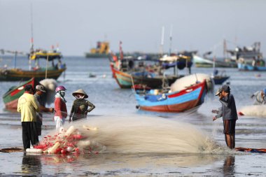 Balıkçılar balık ağlarını onarıyor. Dua hangarını asın. Vung Tau. Vietnam.