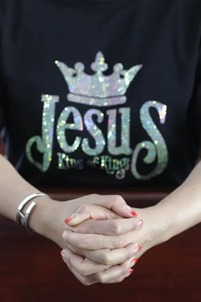 Christian woman  wearing Jesus King of the King T Shirt.  Woman praying.