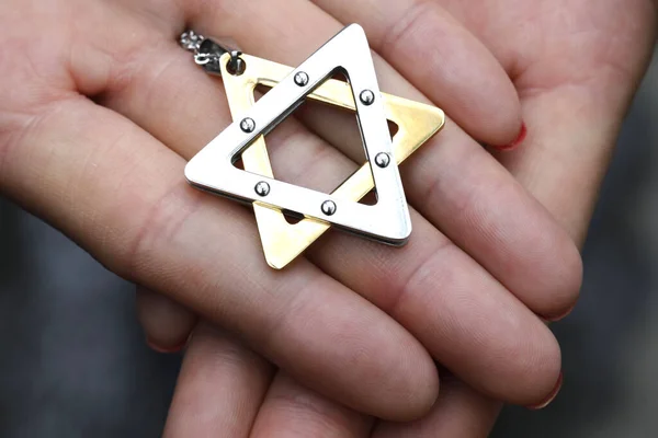 Woman with a Star of David  or Jewish Star pendant. Close up on hands.