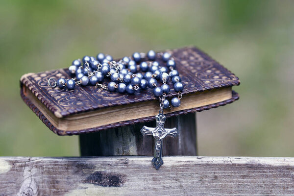 Bible and  catholic rosary beads on wood. 