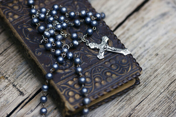 Bible and  catholic rosary beads on wood. 