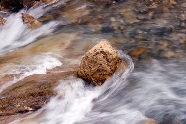 Dağ nehri kayaların üzerinden akıyor. Nehrin dibi taşlı. Şelaleler çağlıyor. Les Contamines. Fransa. 