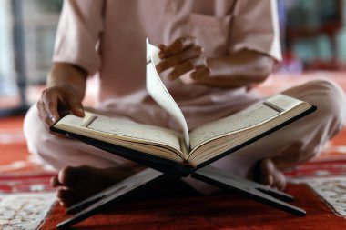 Mübarek camii. Mescid-i Haram 'da oturan ve Kuran' ı okuyan müslüman bir adam. Vietnam. 