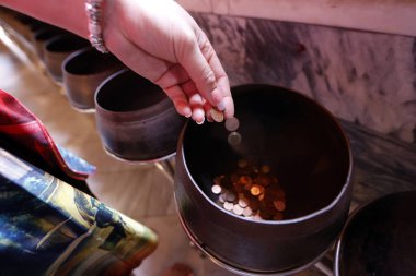 Wat Pho tapınağı. Kutsanmak ya da iyi şans aramak için çömlekteki madeni paralara tapıyoruz. Bangkok 'ta. Tayland.