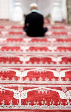 Müslüman bir adam camide namaz kılıyor. Yeşil halılı dua salonu.