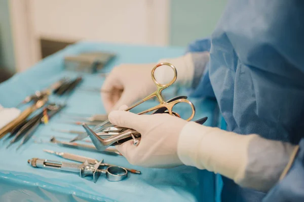 Nurse doctor preparing surgical equipment for operation inside emergency hospital room - Focus on hand holding scissors