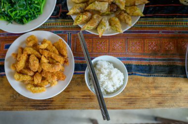 Top view of seaweed and rice with rolls and batter fried shrimps placed on plates with chopsticks on wooden table