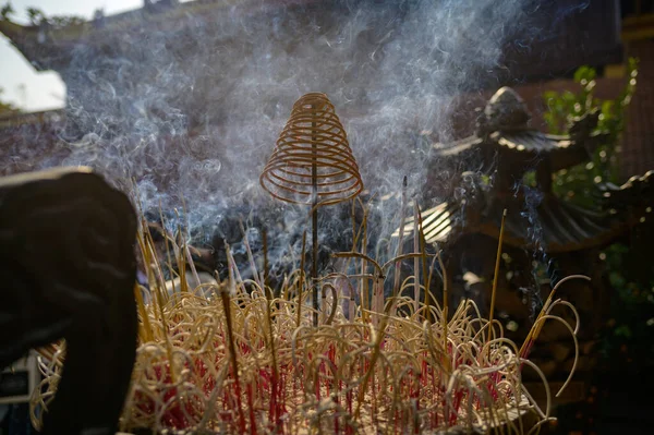 stock image Aromatic smoking incense in garden with statues and dry grass against green tree during ceremony on sunny day