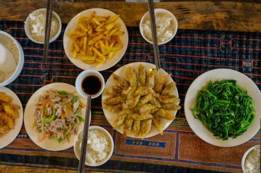 Salata yakınındaki yosun ve deniz yosunu da dahil olmak üzere çeşitli Vietnam sokak yemeklerinin en üst görüntüsü ve pilav ve soya sosuyla servis edilen kızarmış patates bambu çubuklarıyla servis edilen soya sosu.