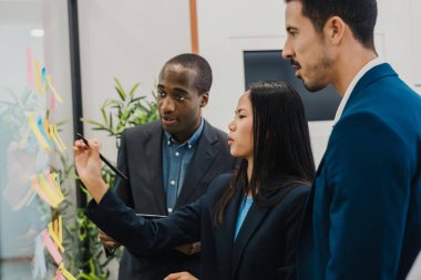 Modern ofiste cam duvarın yanında duran çok ırklı iş arkadaşlarının yan görünüşü.