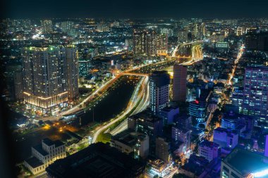 Gökdelenleri olan çağdaş renkli şehir manzarası ve geceleri parlayan ışıklarda otoyolları olan modern apartmanlar.