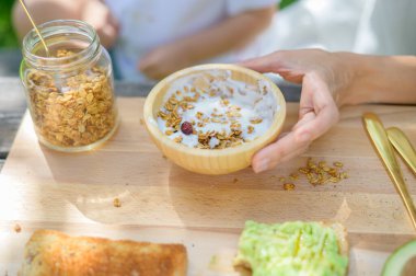 İsimsiz bir kadın ve çocuğun, parkta piknik yaparken tahtanın yanındaki masada oturup yoğurt ve tahıl ve böğürtlen hazırlamasından.