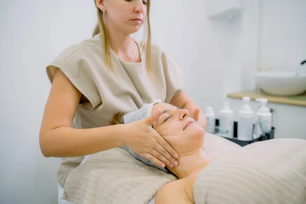 Crop Cosmetologo Femminile Massaggio Viso Rilassato Cliente Mezza Età Durante — Foto Stock