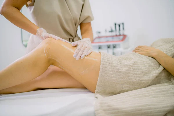 Anonym Massageterapeut Handskar Smeta Lotion Benet Kvinnlig Klient Arbetet Kosmetologi — Stockfoto