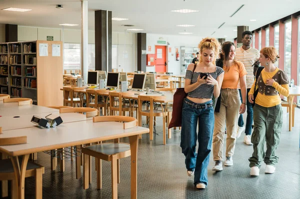 Modern Üniversitenin Hafif Kütüphanesinde Masaların Yanında Yürürken Akıllı Telefon Kullanan — Stok fotoğraf