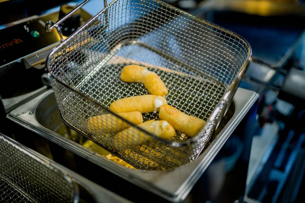 Fast food restoranındaki kızartma makinesinde kızartılmış iştah açıcı peynirli çubuklar.
