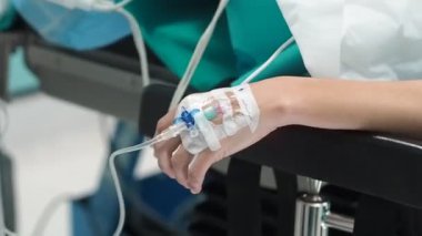 Hastanedeki ameliyattan önce beyaz bornozlu bir doktorun baygın hastaya tüpler yerleştirirken yüksek açılı el kamerası görüntüsü.