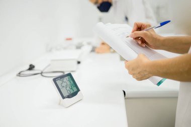 İlaçların laboratuvarda depolanması için sıcaklığı kontrol ederken belgeye notlar alan anonim bileşik eczacının ürünleri