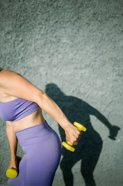 Aydınlık Aktif Giysili Sportif Bir Kadının Gri Duvarda Halterli Trisepslerden — Stok fotoğraf