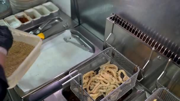 식품점에서 패스트푸드를 준비하는 통속으로 고리가 프라이어를 요리하는 익명의 요리사의 각도의 — 비디오