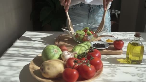 新鮮な果物や野菜を木製のへらやフォークで混ぜながら キッチンで健康的なサラダを準備しながら 作物の匿名の女性のハンドヘルドショットでズーム — ストック動画
