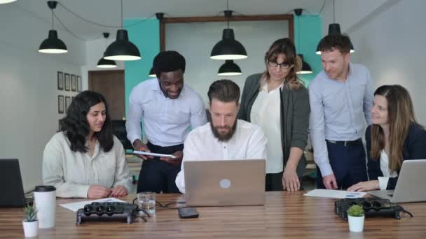 ノートパソコンでプロジェクトに協力し オフィスでの勤務中に笑う正式な服を着た多様な男性と女性のビジネスマンのグループ — ストック動画