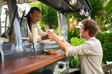 Yazın güler yüzlü erkek müşterinin yiyecek kamyonundan içecek alışının yan görüntüsü