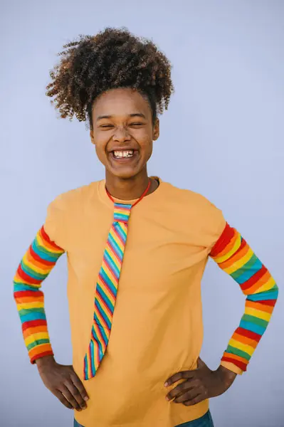 身穿橙色套头衫 头戴彩虹袖子 戴着领带 紧闭双眼 蓝底带着微笑的快乐的非洲裔美国女性 — 图库照片