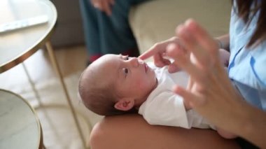 Yüksek açılı el kamerası, anne gıdıklanırken yanak, kollar ve bacaklara dokunurken evdeki güneşli oturma odasında, kanepede otururken.