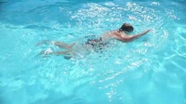 Yaz tatilinde mayo giymiş, havuzda yüzen olgun bir kadının yavaş çekim çekimi.