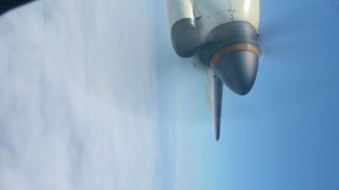 Güneşli yaz gününde bulutlu gökyüzüne karşı uçan uçak penceresinden görülen pervane.