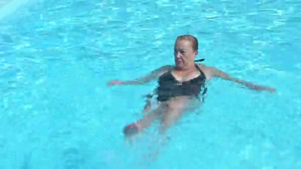 上記のショットから 夏休み中にリゾートで青い水とプールで泳ぐ水着の成熟したフィット女性 — ストック動画