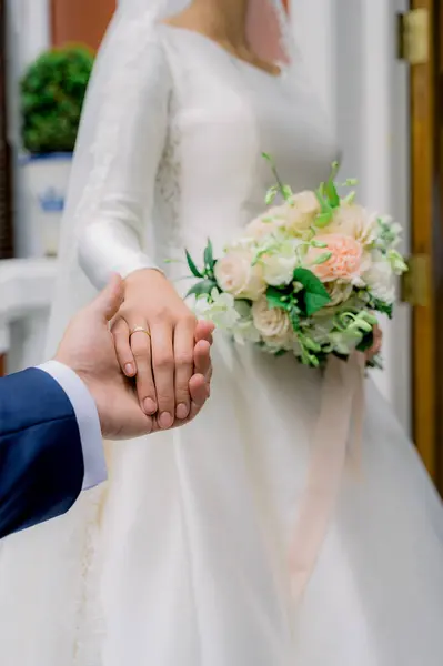 婚礼期间 身穿西服的新郎牵着新娘的手 头戴金戒指 身穿白色婚纱 手持花束 — 图库照片