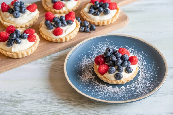 An assortment of berry tarts on a rustic white table.